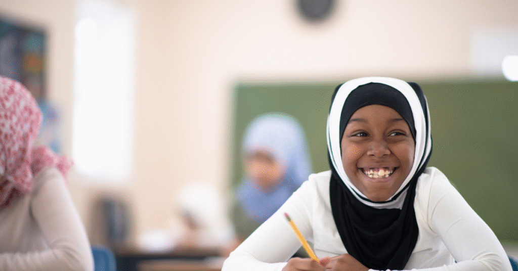 Smiling Muslim schoolgirl studying during Quran classes for kids in a classroom learning environment