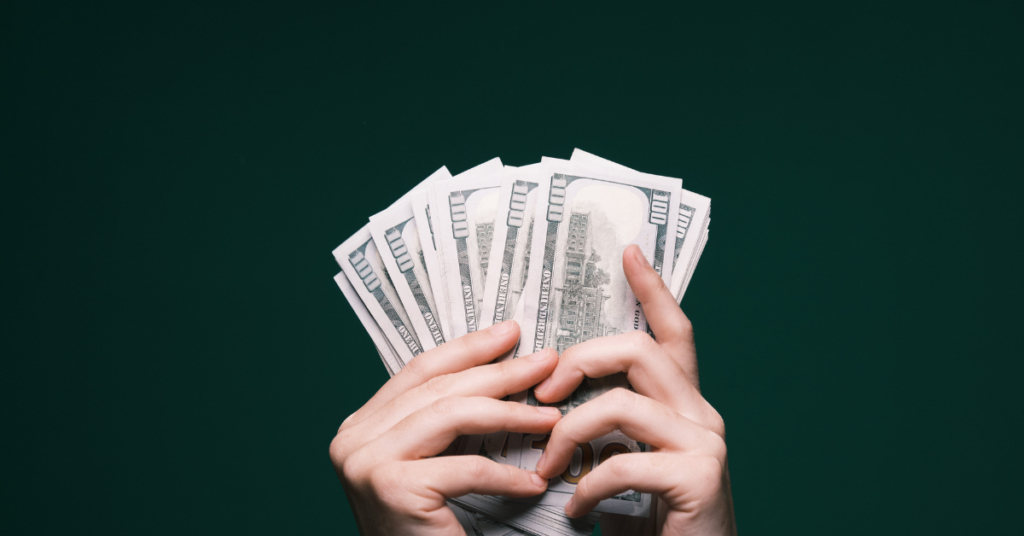 Hands holding US dollar bills representing the cost of online Quran classes in USA